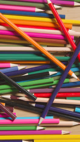 Vertical-Video-Of-Random-Coloured-Pencils-On-Wooden-Background-With-Person-Picking-Purple-Pencil